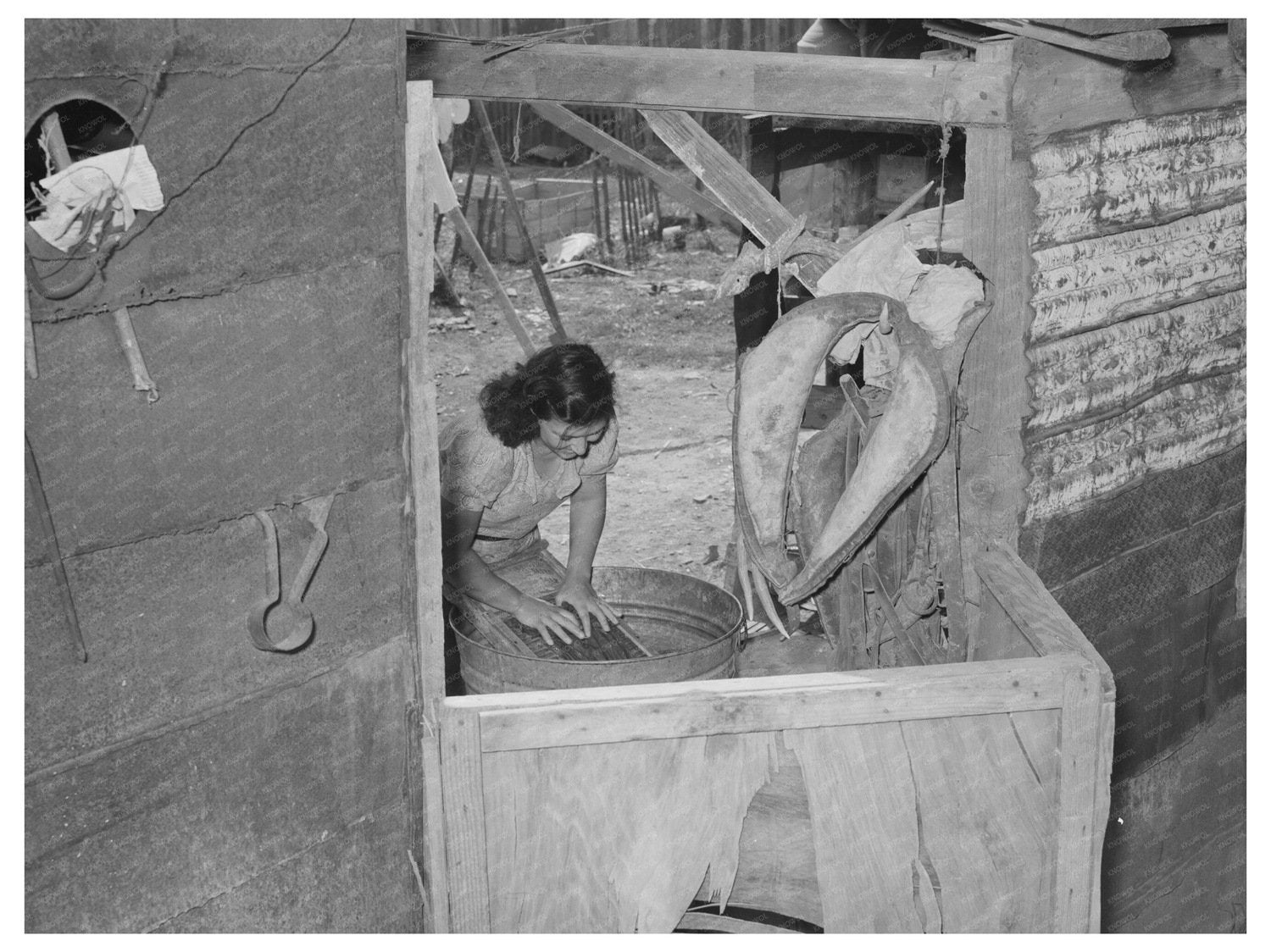 Mexican woman washing clothes in back of house. Sa