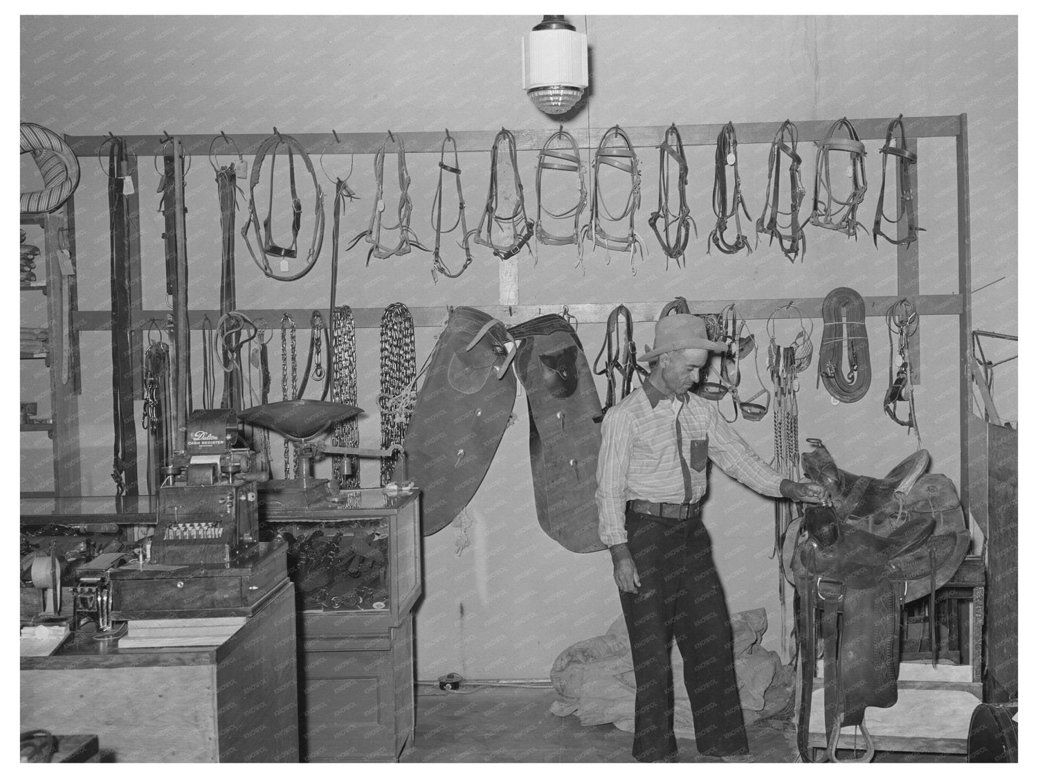 Cowboy Examining Saddle in Brewster County Texas 1939 - Available at KNOWOL