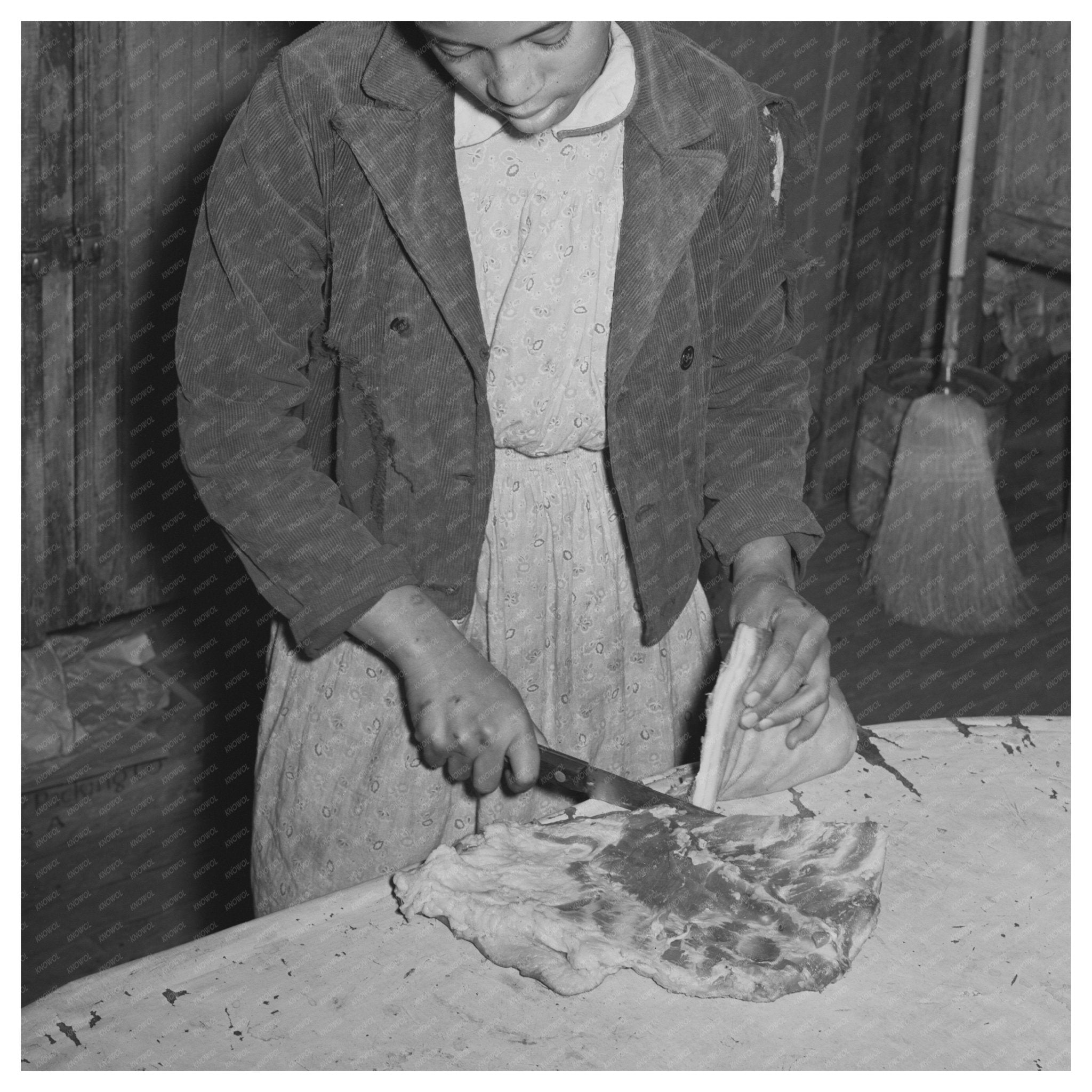 Daughter of Tenant Farmer Slicing Bacon February 1940 - Available at KNOWOL