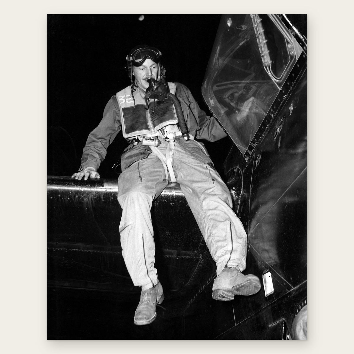 Capt. Donald R. DeFoe in a flying helmet, goggles and life vest, with his oxygen mask at his mouth, climbs out of the open canopy of his black B-26 bomber at night, restored vintage photo print