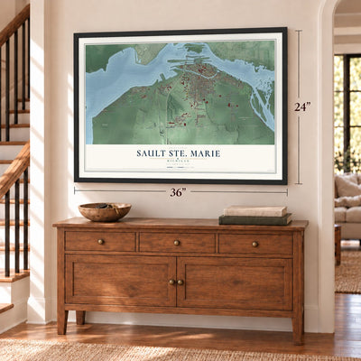 Sault Ste. Marie, Michigan map, 24 x 36 inch print in a black frame above a dresser by a staircase